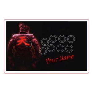 Puede incluir: Panel de palanca de mando arcade negro con una ilustración roja de un personaje y un símbolo en la espalda. Tiene ocho contornos de botones blancos y el texto "Your Name" en rojo.