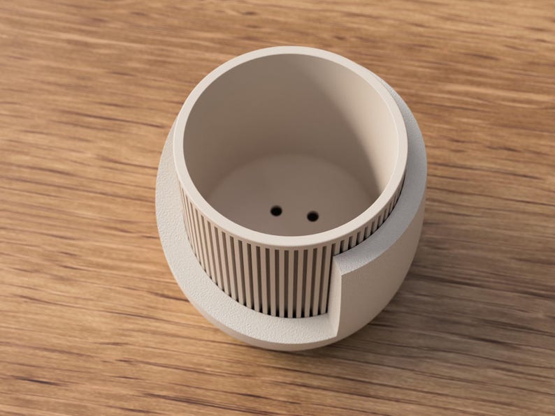 May include: A light beige, modern planter with a cylindrical interior and a decorative, vertical-lined exterior. The planter has two drainage holes and is made of a smooth, matte material. The planter is approximately 4 inches in diameter.