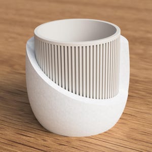 May include: A white, modern-style mug with a unique design. The mug features a cylindrical inner cup with vertical lines, set within a curved, textured outer shell. The design is minimalist and contemporary, suitable for home decor.