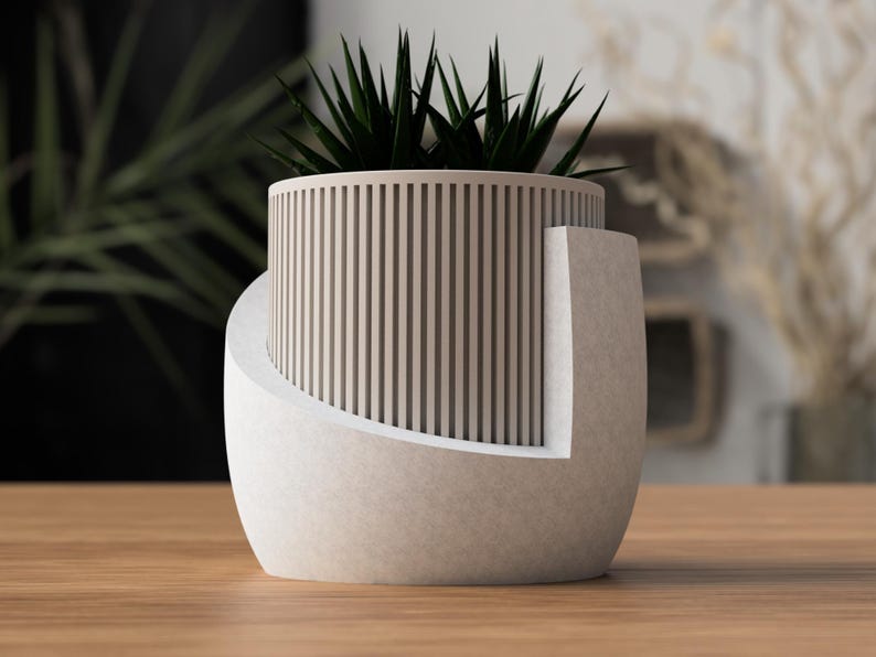 May include: A modern, two-tone planter with a cylindrical, slatted upper section and a curved, solid base. The planter holds a dark green succulent plant. The design features a neutral color palette, suitable for various interior styles.