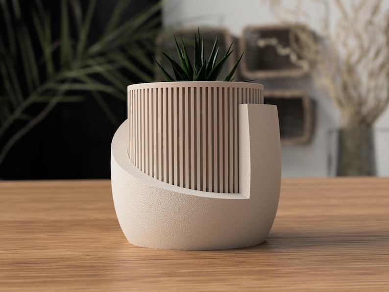 May include: A modern, beige-colored planter with a cylindrical, slatted design. The planter has a curved base and holds a small, green succulent. The design is minimalist and suitable for indoor decor.