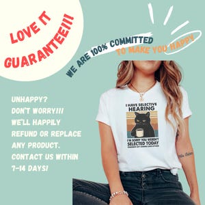 May include: White t-shirt with a graphic of a black cat holding a mug, text reads "I have selective hearing" and "I'm sorry you weren't selected today". The shirt also has text that says "Tomorrow isn't looking good either".