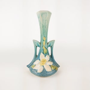 May include: A blue and white ceramic vase with a floral design. The vase has two handles and a narrow neck.