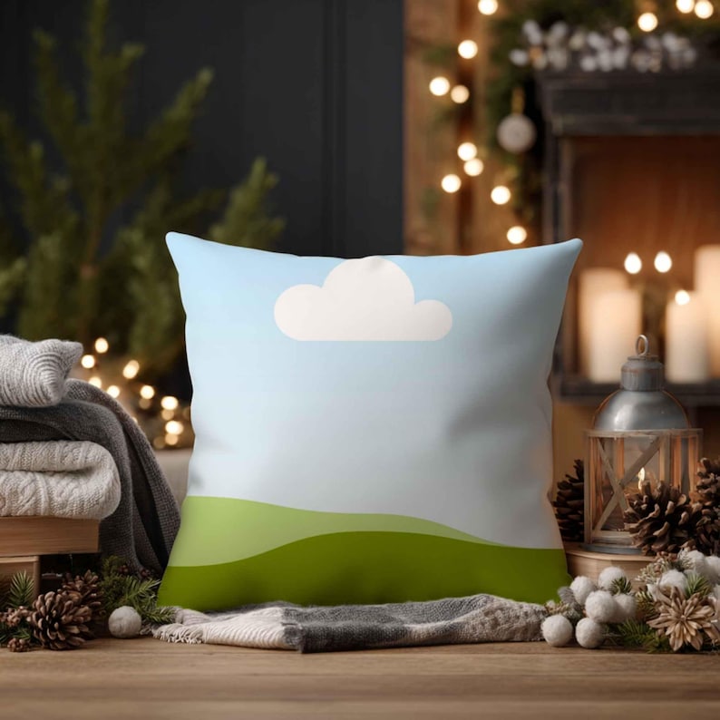 May include: A square cushion with a whimsical landscape design. The cushion features a light blue sky with a white cloud and green rolling hills. The cushion is placed on a wooden surface with decorative elements.