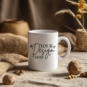 May include: White ceramic mug with a curved handle, featuring the text "YOUR Design HERE" in a stylish script. The mug is set on a neutral-toned surface with walnuts and burlap accents, creating a warm, inviting aesthetic.