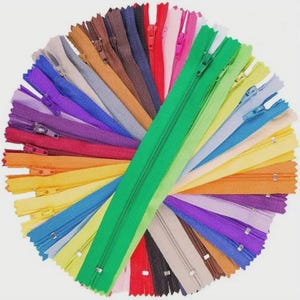 May include: A collection of colorful zippers arranged in a circular pattern. The zippers are in various colors, including green, red, yellow, blue, purple, and brown. The image is taken from a top-down perspective, showcasing the variety of colors and styles.