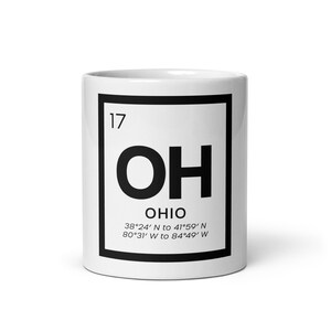Puede incluir: Taza de cerámica blanca con un cuadrado negro que contiene las letras "OH" en negrita, en negro. Debajo, la palabra "OHIO" y coordenadas. El número "17" está en la esquina superior izquierda del cuadrado.