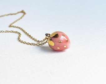 Charm de fresa de porcelana hecho a mano con detalles dorados.