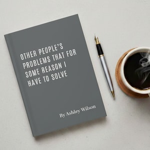 Può includere: Un libro grigio con il titolo "OTHER PEOPLE'S PROBLEMS THAT FOR SOME REASON I HAVE TO SOLVE" di Ashley Wilson. Una penna d'argento con pennino dorato e una tazza di caffè su un sottobicchiere sono accanto al libro.