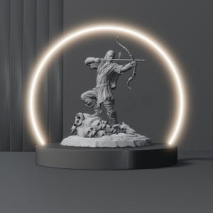 May include: A grey statue of an archer drawing a bow, standing on a base of skulls and a rocky surface. The statue is illuminated by a glowing circular light against a dark grey background. The archer is dressed in period clothing.
