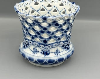 May include: A white and blue porcelain basket with a delicate openwork design. The basket features a scalloped rim and a detailed floral pattern around the base. The blue and white color scheme gives it a classic, elegant look.