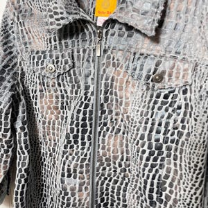May include: A gray, black, and brown patterned jacket with a zipper closure and two front pockets. The jacket has a collared neckline and a textured, reptile-like design. The brand tag "Ruby Rd" is visible.