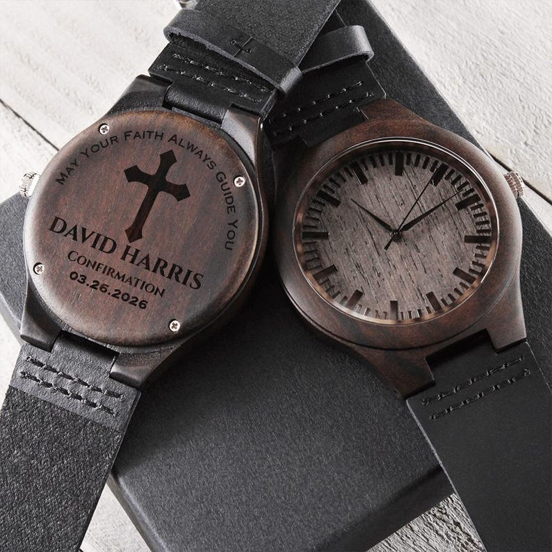 May include: Two wooden watches with black leather straps. One watch face has a cross and the inscription "MAY YOUR FAITH ALWAYS GUIDE YOU" and the name "DAVID HARRIS" with "CONFIRMATION 03.26.2026". The other watch face has a wood grain design.