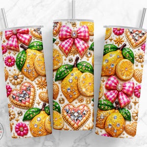 May include: Three stainless steel tumblers with a decorative design featuring lemons, bows, hearts, and flowers. The design incorporates pink, yellow, green, and gold colors, with rhinestone accents. Each tumbler has a silver straw.