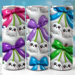 May include: A cylindrical tumbler featuring a repeating pattern of white ghost-shaped figures with smiling faces, each paired with a colorful bow in shades of pink, purple, blue, or green, connected by green stems resembling a cherry motif.