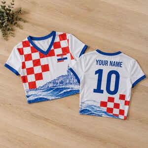 A white and red soccer jersey with a blue and white cityscape design, along with the text "YOUR NAME 10" printed on the back.