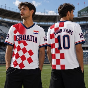A man wearing a white and red Croatia soccer jersey stands on a soccer field.