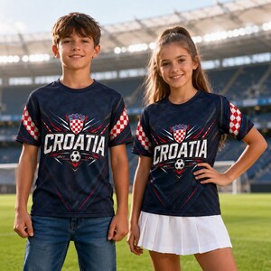 A young boy and girl wearing matching Croatia soccer jerseys stand together on a soccer field.