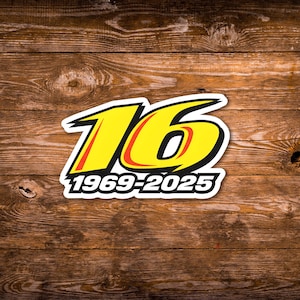 May include: A sticker featuring the number "16" in yellow with a red outline and a white border. The text "1969-2025" is below the number in white. The sticker is set against a wooden background.