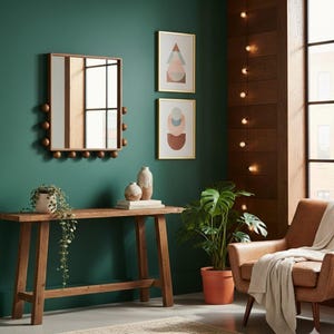 Puede incluir: Una habitación con una consola de madera, un sillón de cuero marrón y un espejo con esferas de madera. Dos obras de arte abstractas enmarcadas cuelgan de la pared verde. Una planta en maceta y jarrones decorativos están sobre la mesa.