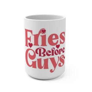 Może przedstawiać: Biały ceramiczny kubek z napisem "Fries Before Guys" w czerwonym skrypcie. Słowa są zaakcentowane małymi kształtami serca. Kubek jest cylindryczny i ma duży uchwyt.