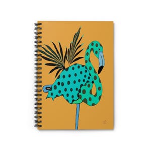 May include: Spiral-bound notebook featuring a whimsical illustration of a flamingo with teal polka dots and black accents against a mustard yellow background. The flamingo has a blue beak and is adorned with black leaf-like details.