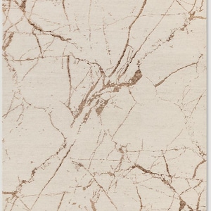 May include: A rectangular rug with a cream-colored background and a brown, marble-like veining pattern. The veining creates a natural, organic design across the surface of the rug. The rug has a soft, textured appearance.