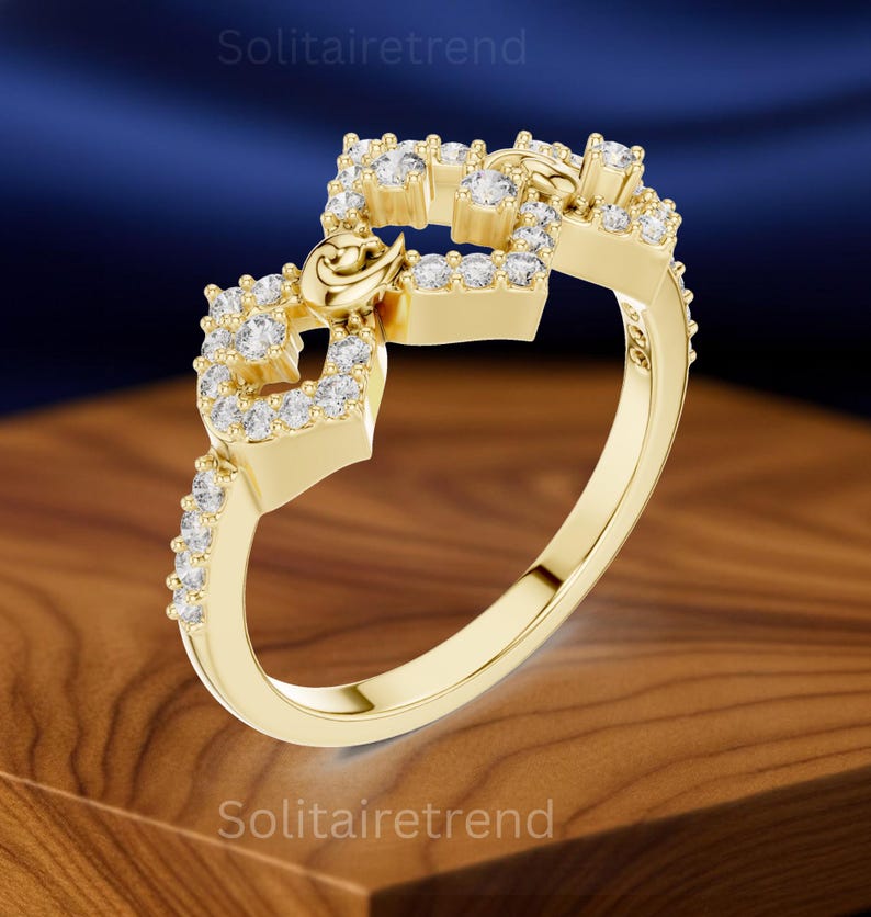 Puede incluir: Un anillo dorado con un dise&ntilde;o &uacute;nico. El anillo presenta una serie de formas cuadradas adornadas con peque&ntilde;as piedras preciosas transparentes. Un peque&ntilde;o elemento decorativo est&aacute; centrado en el anillo. El anillo se muestra sobre una superficie de madera.