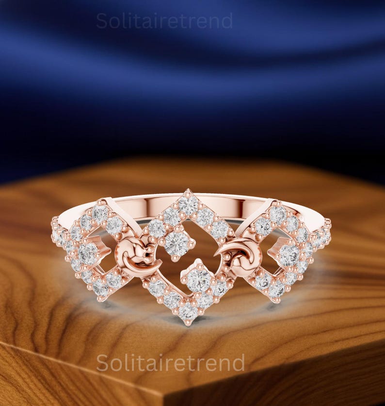 Puede incluir: Anillo de oro rosa con un dise&ntilde;o geom&eacute;trico, con m&uacute;ltiples piedras preciosas redondas y transparentes. El anillo tiene una forma &uacute;nica con espacios abiertos y elementos decorativos.