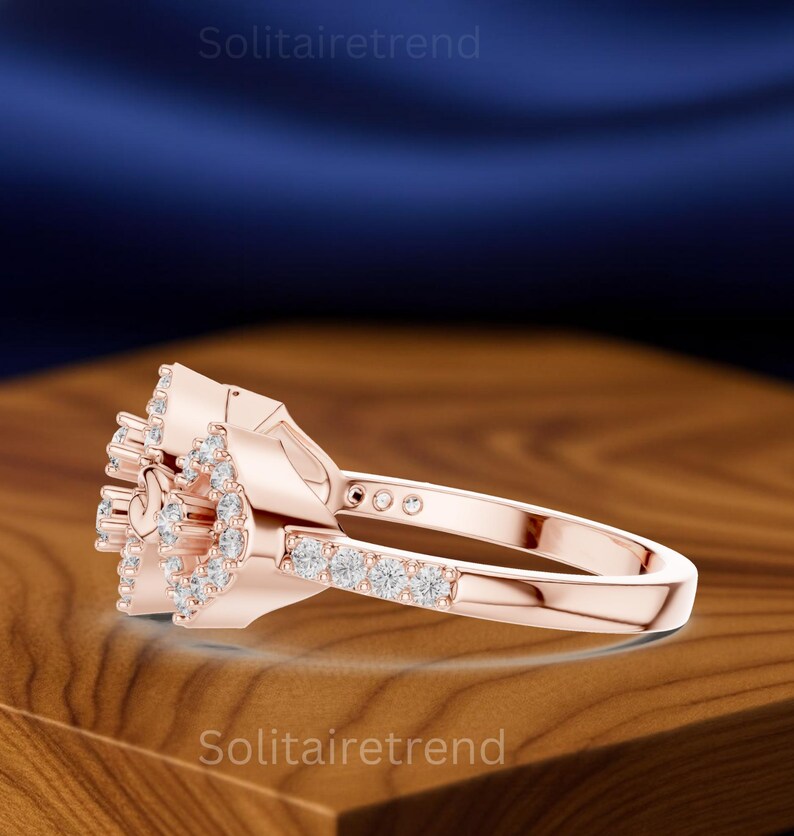Puede incluir: Anillo de oro rosa con dise&ntilde;o floral, con m&uacute;ltiples piedras preciosas peque&ntilde;as y transparentes. La banda del anillo es lisa y el engaste muestra un grupo de piedras. El nombre de la marca "Solitairetrend" es visible.