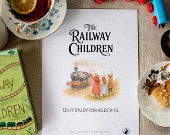 Puede incluir: Vista aérea de un libro y una guía de estudio titulada "The Railway Children" con una ilustración de tren. También hay una taza de té con limón, una porción de pastel y vagones de tren de juguete. La guía de estudio es para niños de 9 a 12 años.