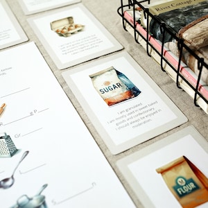 Puede incluir: Un conjunto de tarjetas ilustradas y una hoja de trabajo relacionadas con la reposter&iacute;a. Las tarjetas presentan im&aacute;genes de acuarela de ingredientes como az&uacute;car y harina, con texto descriptivo. Una cesta de alambre contiene libros y una hoja de trabajo muestra utensilios de cocina.
