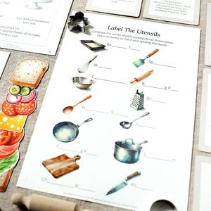 Puede incluir: Material educativo con tem&aacute;tica de cocina. Incluye una hoja de trabajo titulada "Label The Utensils" con ilustraciones de utensilios de cocina, tarjetas de recetas y un marcap&aacute;ginas con forma de s&aacute;ndwich. Ilustraciones de estilo acuarela.