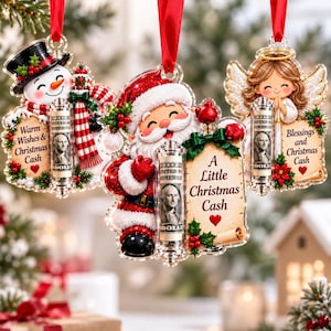May include: Three hanging Christmas ornaments featuring a snowman, Santa Claus, and an angel. Each ornament includes a clear cylindrical tube holding a rolled one-dollar bill and text reading Warm Wishes, A Little Christmas Cash, or Blessings.