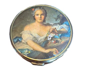 Die antike Messing Puderdose zeigt ein zartes Damenporträt in Blumenmuster.