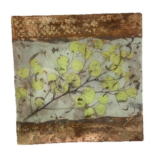 May include: Square artwork featuring a sprig of green leaves on a light blue background. The artwork has a copper-colored border with a textured, aged appearance. The leaves are a pale green color.