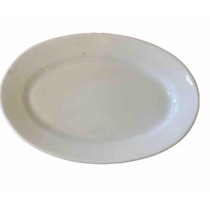 May include: A plain white oval serving platter with a smooth, glossy finish. The dish features a simple, wide rim and a shallow center basin. There are faint, small brown spots visible on the surface of the white ceramic material.