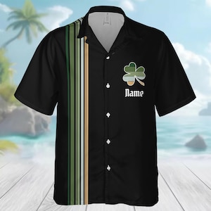 May include: Black button-up shirt with a shamrock design and the word "Name" in white script. The shirt features a vertical stripe design in green, white, and tan. Short-sleeved, the shirt is suitable for casual wear.