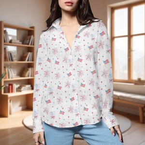 K&ouml;nnte beinhalten: Wei&szlig;es Button-Down-Hemd mit einem Muster aus roten, wei&szlig;en und blauen Feuerwerksk&ouml;rpern, amerikanischen Flaggen und Sternen. Das lang&auml;rmlige Hemd hat einen klassischen Kragen und ist aus leichtem Stoff gefertigt. Das Hemd ist am Ausschnitt aufgekn&ouml;pft.