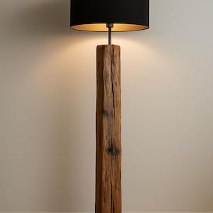 Pode incluir: Candeeiro de p&eacute; r&uacute;stico com abajur preto e interior dourado. O candeeiro apresenta uma base de poste de madeira castanha desgastada e uma base quadrada de metal preto. O candeeiro tem aproximadamente 152 cm de altura.