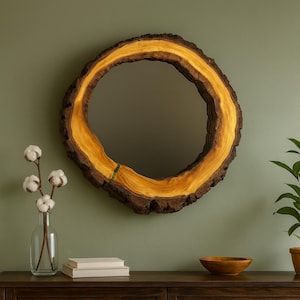 Peut inclure: Un miroir rond avec un cadre en bois naturel. Le cadre a un bord extérieur brun foncé et texturé et un anneau intérieur jaune-or vif. Le miroir est monté sur un mur vert, avec un vase de tiges de coton et un bol en bois sur une surface en bois foncé.