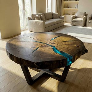 May include: A round coffee table featuring a natural wood slab top with a live edge and visible grain. A vibrant, translucent turquoise resin inlay fills the cracks and fissures across the surface. The table stands on a dark metal base.