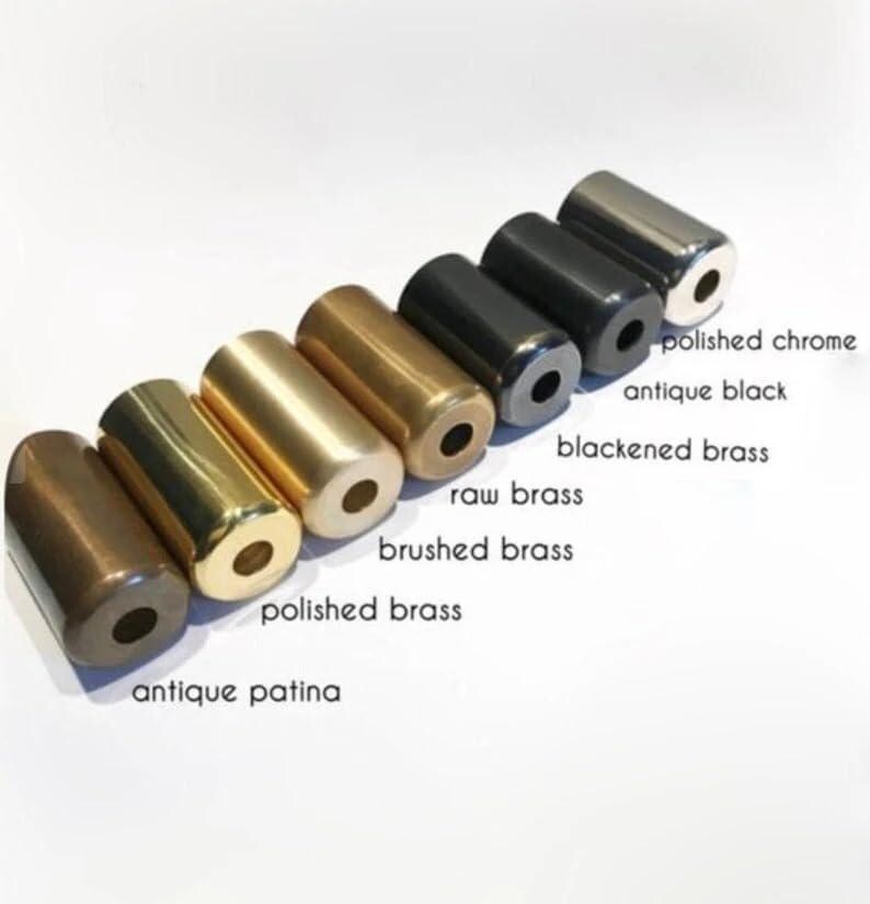 May include: An assortment of cylindrical metal objects in various finishes, including antique patina, polished brass, brushed brass, raw brass, blackened brass, antique black, and polished chrome. Each cylinder has a hole at one end. The objects are arranged diagonally.