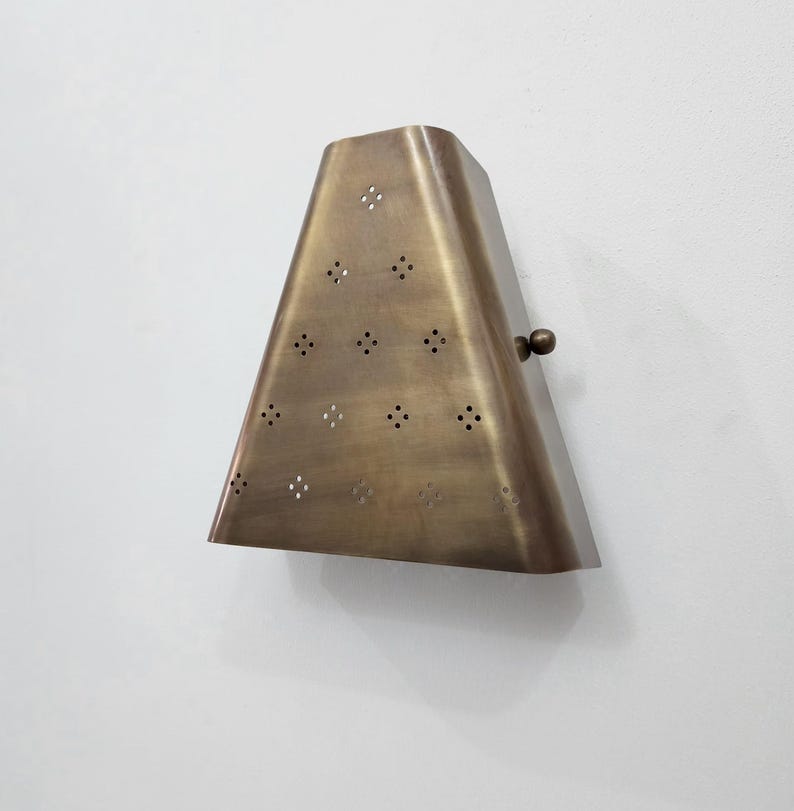 Handcrafted brass wall sconce featuring a tapered geometric form with dotted texture and side fixing knob.