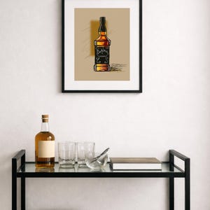 May include: A framed print of a whiskey bottle with a black label and a brown background. The print is in a black frame. A shelf below holds a bottle, glasses, and books.