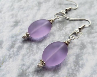 May include: A pair of silver dangle earrings with lavender glass oval beads.