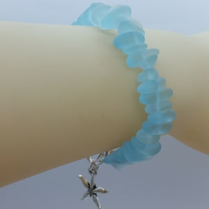 Pu&ograve; includere: Un braccialetto in vetro di mare blu chiaro con un ciondolo a forma di stella marina argentata.