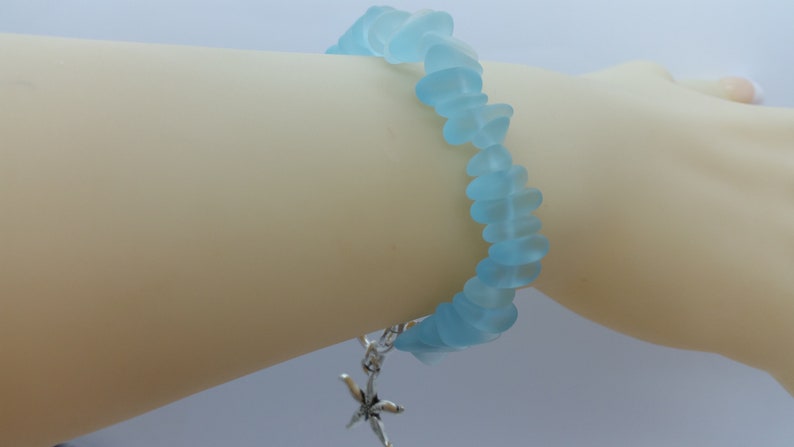 Pu&ograve; includere: Un braccialetto in vetro di mare blu chiaro con un ciondolo a forma di stella marina argentata.