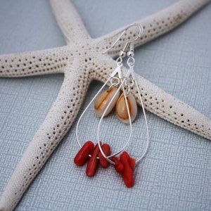 May include: Silver dangle earrings with a teardrop-shaped shell and coral accents.