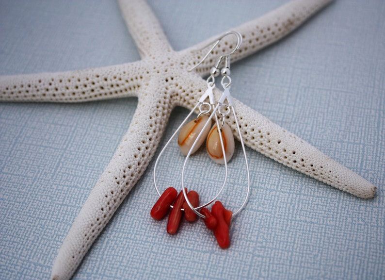 May include: Silver dangle earrings with a teardrop-shaped shell and coral accents.